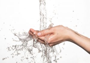 closeup female hands under the stream of splashing water - skin care concept