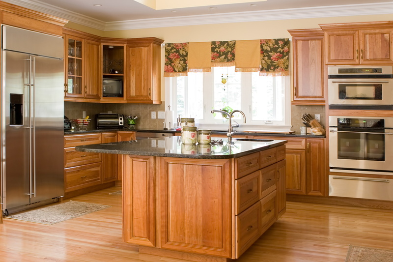 a pristine looking kitchen with wood flooring, island, and cabinets