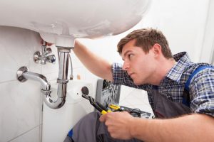 Portrait of male plumber fixing a sink in bathroom