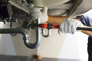 gloved-hands-under-sink-working-on-plumbing
