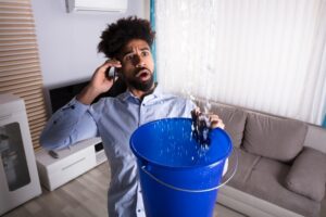 man-catching-water-from-ceiling-in-bucket